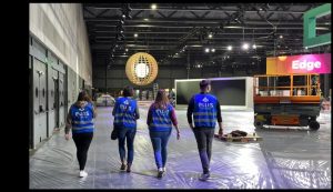 Four ellis EVENTS employees, dressed in branded warning vests are walking throuhg the exhibition area